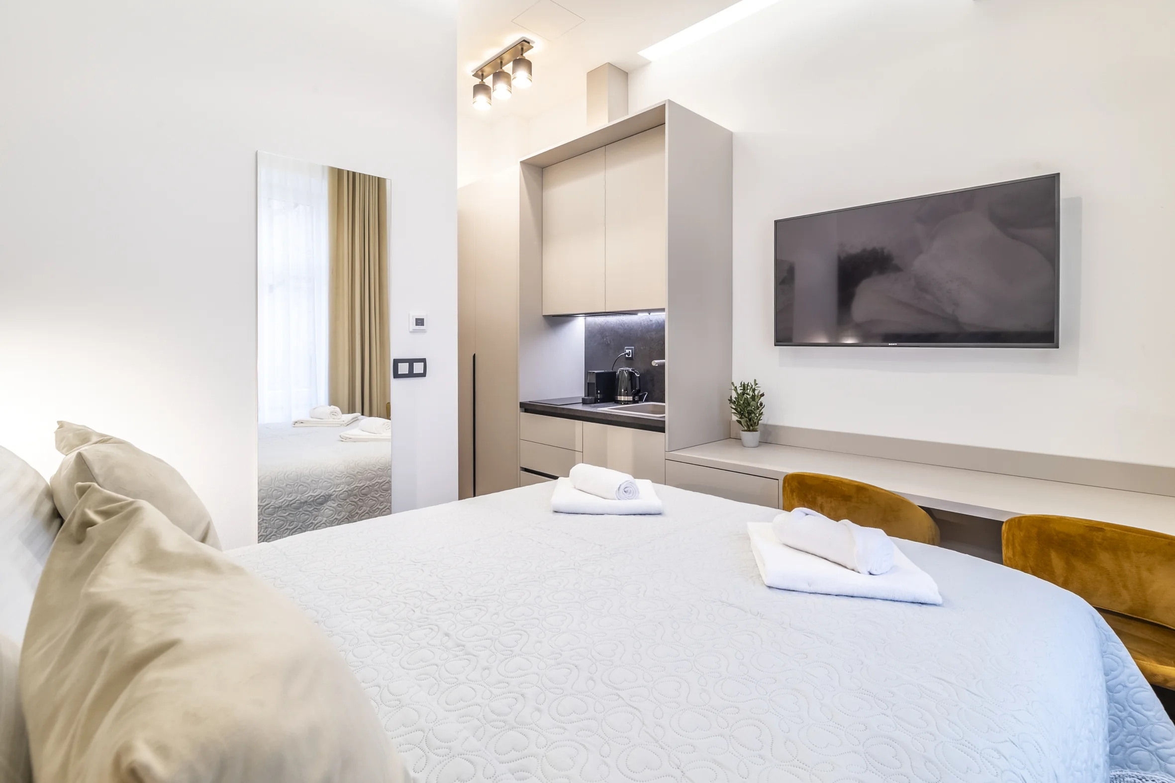 Studio apartman: queen krevet, televizor na zidu, kuhinja i zlatne fotelje